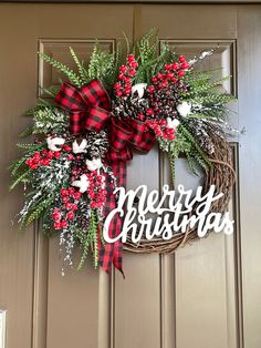 a christmas wreath with the words merry christmas written on it and red berries, pine cones, and evergreens