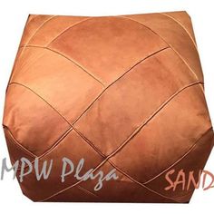 a large brown leather poufce with braiding on the sides and bottom, sitting in front of a white background