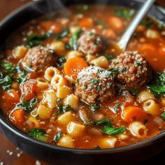 a bowl of soup with meatballs, carrots and spinach