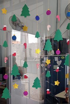 christmas tree decorations hanging from the ceiling in front of a window