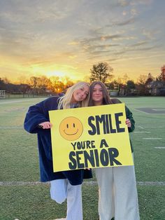 two women holding up a sign that says smile you're a senior