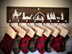 christmas stockings hanging on a wooden sign with nativity scene