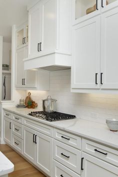 a kitchen with white cabinets and wooden floors