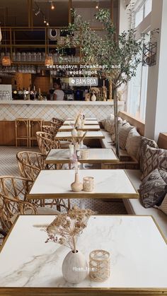 tables and chairs are lined up in a restaurant with white marble top, gold trim