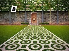 an intricately designed walkway in front of a stone building with grass growing on the ground