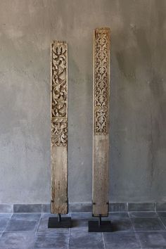 two wooden sculptures sitting on top of a tile floor next to each other in front of a wall