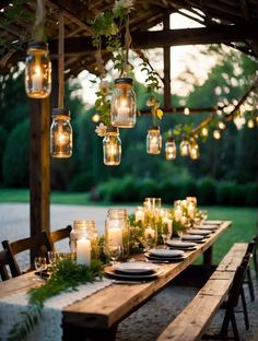 an outdoor dining table with mason jars hanging from the ceiling and candles lit up on it