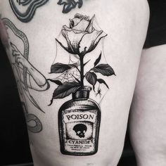 a woman's thigh with a bottle and rose tattoo on it