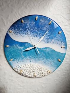 a blue and white clock with sea shells on it's face is hanging from the wall