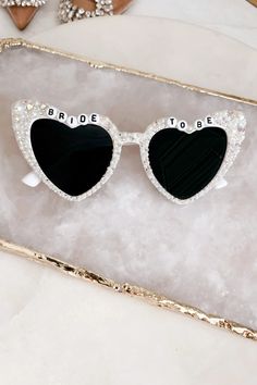 the bride to be heart shaped sunglasses are on display in a gold box with pearls