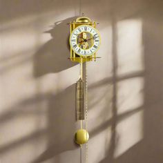 a yellow clock hanging from the side of a wall