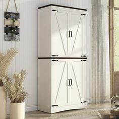 a white cabinet with two doors in a living room next to a potted plant