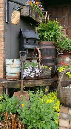 an outdoor garden with lots of flowers and plants on the side of a brick building