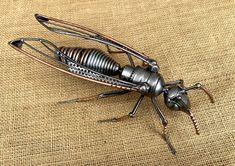 a large metal insect sitting on top of a piece of cloth