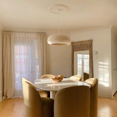 the dining room table is surrounded by beige chairs and an oval light fixture hanging from the ceiling