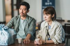 a man sitting next to a woman at a table with a coffee cup in front of her