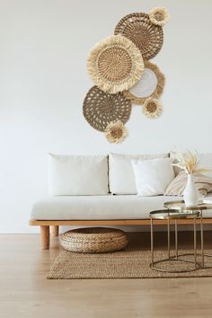 a living room with white couches and wicker wall hangings on the wall