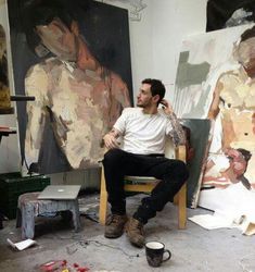 a man sitting in a chair next to some paintings