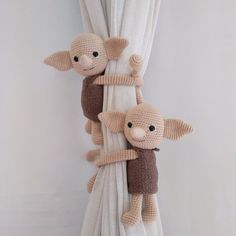 two stuffed animals hanging from the side of a white curtain in front of a window