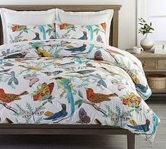 the comforter is made up with colorful birds and plants on it's bed