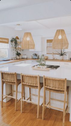 a large kitchen island with three stools in front of it and two lamps hanging from the ceiling