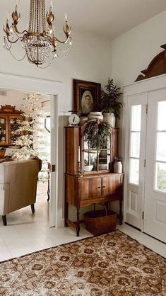 a living room filled with furniture and a chandelier hanging from the ceiling next to a doorway