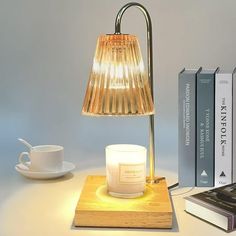 a table with a lamp, books and a candle on it next to a coffee cup