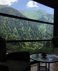 a living room filled with furniture and a large window covered in forest view overlooking the mountains