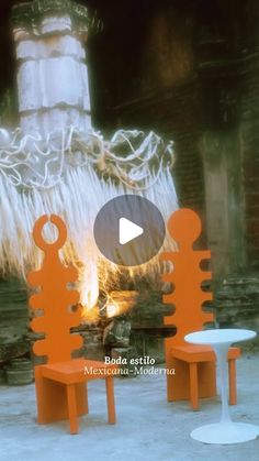 three orange chairs sitting next to each other on top of cement ground with fire in the background