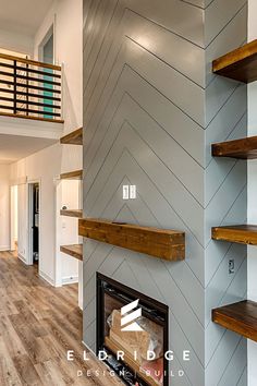 an empty living room with wood flooring and open shelving on the wall next to a fireplace