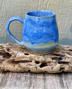 a blue mug sitting on top of a piece of wood