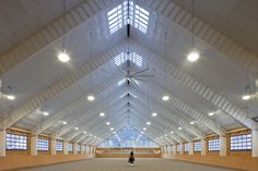 a person standing in the middle of a large room with vaulted ceiling and windows on both sides