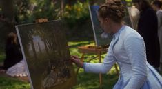 a woman is painting on an easel outside