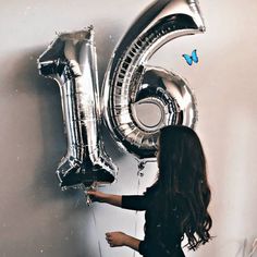 a woman is holding some silver balloons