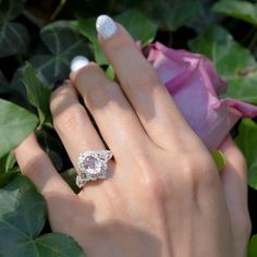 a woman's hand with a ring on it and a rose in the background