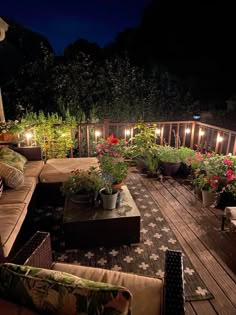 an outdoor deck is lit up with candles and potted plants