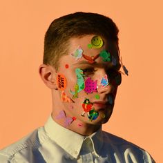 a man with his face covered in colorful stickers and confetti on his face