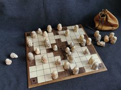 a chess board and pieces of marble on a blue cloth surface with a drawstring bag in the background