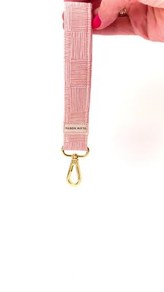 a person holding onto a pink lanyard with a gold ring on it's end