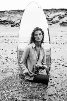 a woman sitting in front of a mirror on the beach