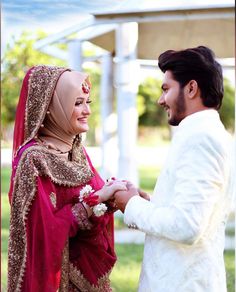 a man and woman standing next to each other in front of a white gazebo