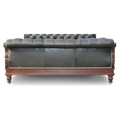 a grey leather couch sitting on top of a wooden frame