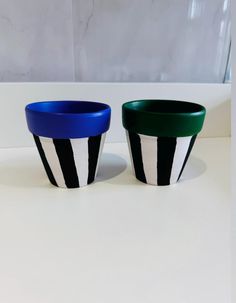 two black and white striped pots sitting next to each other on top of a table