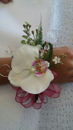 a woman's arm with a white flower and pink ribbon around it, on top of a towel