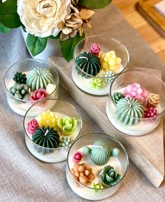 four small glass bowls filled with different types of succulents on a table