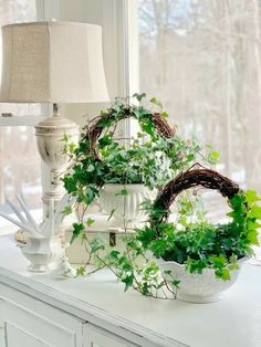 a white table topped with a lamp and potted plant next to a window sill