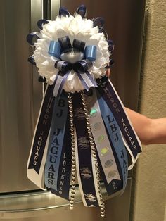 a person is holding a bouquet made out of ribbon and ribbons that are attached to the side of a refrigerator