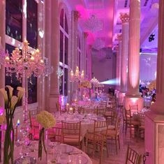 a room filled with lots of tables covered in white clothed cloths and centerpieces