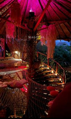 the inside of a restaurant with pink lighting and hammocks on the tables under an umbrella