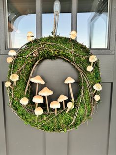 a wreath with mushrooms and moss hanging on the front door to welcome guests into the house